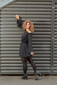 Full length portrait of woman standing against wall