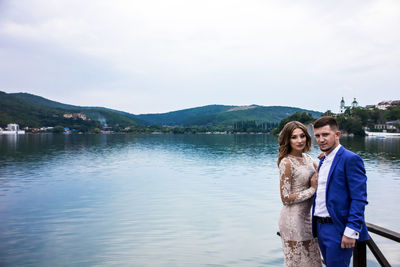 Portrait of couple standing against lake