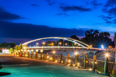 Illuminated bridge over river against sky at night