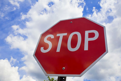 Low angle view of stop sign against cloudy sky