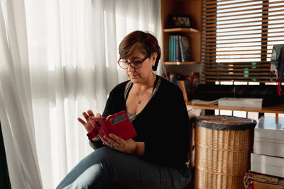 Young woman using phone while sitting at home