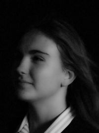 Close-up portrait of young woman against black background