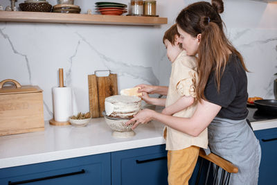 Mother and son baking carrot cake together at cozy kitchen. home cooking, family life