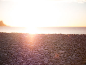 Surface level of pebble beach against sky during sunset