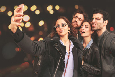 Friends taking selfie while standing outdoors at night