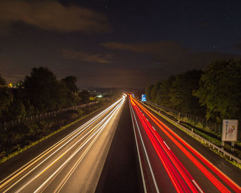 Light trails on road against sky at night