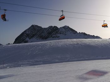 Overhead cable car over snowcapped mountains against sky