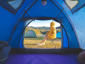 Woman sit front of tent camping around mountain lake under the morning sunlight enjoying.