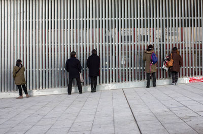 People walking on sidewalk by building in city