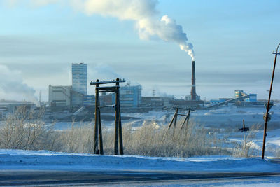 Smoke emitting from factory against sky