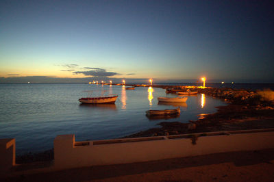 Sailboats in sea at sunset