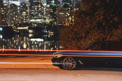 Light trails by car parked on road at night