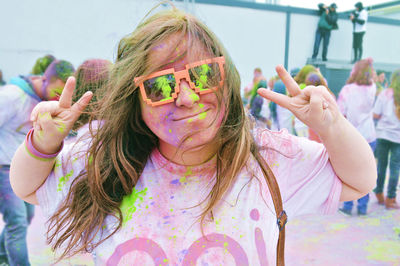 Portrait of young woman with powder paints showing thumbs up signs