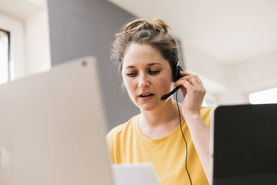 Businesswoman discussing through headphones while working at home