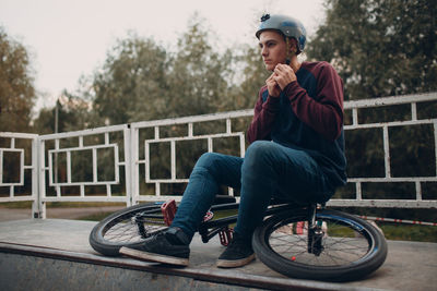 Man fastening helmet while sitting on bicycle