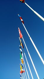 Low angle view of flags hanging against clear blue sky