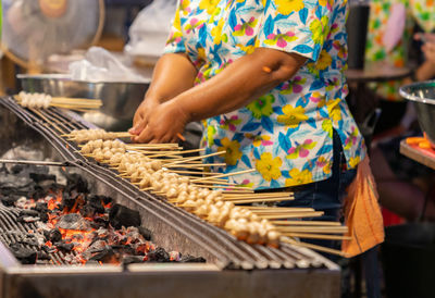 Woman grilling the meat ball with chracoal in street food market.