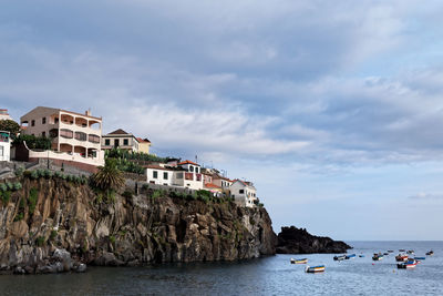 Buildings by sea against sky