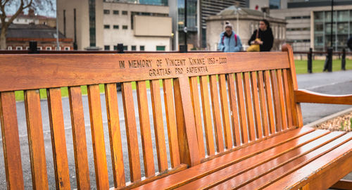 Text on railing by footpath in city against buildings