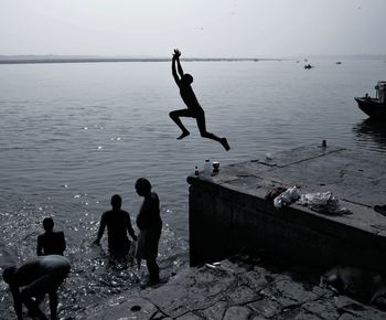 People jumping on beach against sky