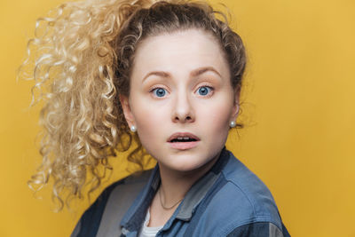 Portrait of young woman against yellow wall