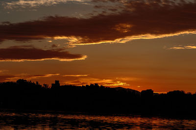 Silhouette trees by sea against sky during sunset