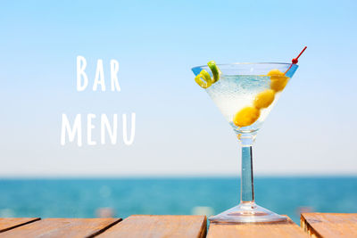 Close-up of drink in glass on table against sea