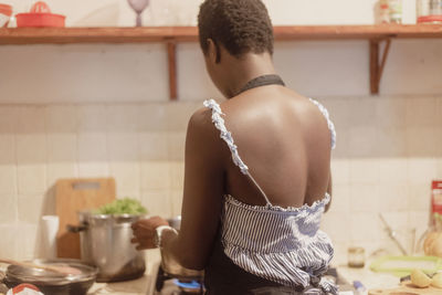 Rear view of young woman standing at home