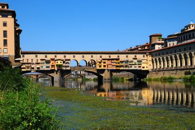 Arch bridge over river against clear blue sky