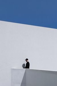 Low angle view of man standing against white wall