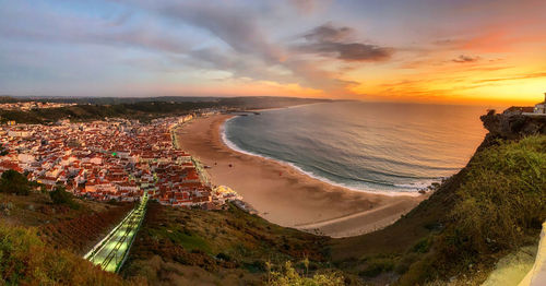 High angle view of townscape by sea against sky during sunset