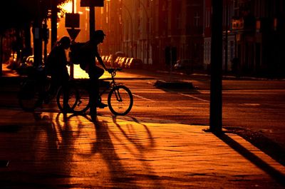 Silhouette man riding bicycle on street at night