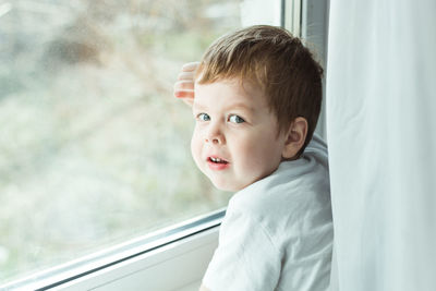 Side view of cute girl looking through window