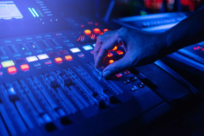 Close-up of hand adjusting music on sound mixer in nightclub