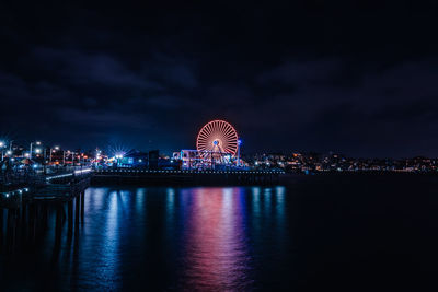 Illuminated ferris wheel in city at night