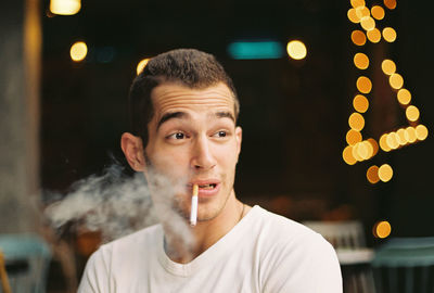 Young man smoking cigarette while sitting in restaurant