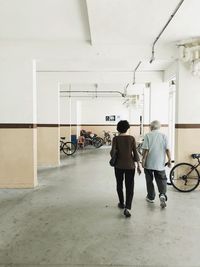 Rear view of people standing on bicycle