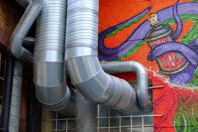 Low angle view of air ducts on graffiti wall