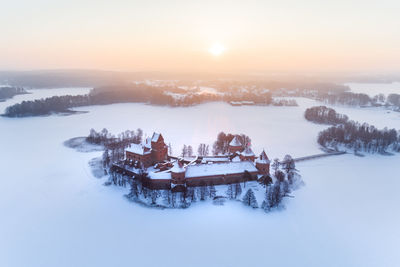 Scenic view of snow and buildings against sky during sunset