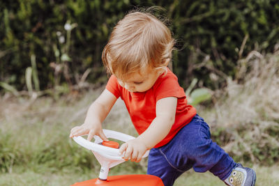 Full length of girl sitting on toy car at field