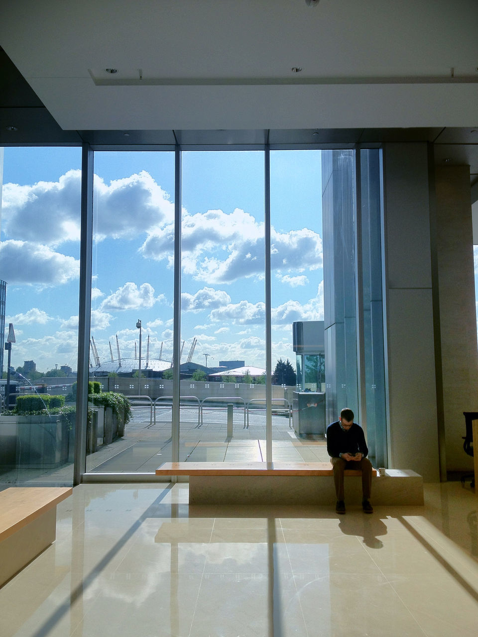 indoors, window, architecture, built structure, glass - material, transparent, sky, building exterior, city, day, looking through window, cloud - sky, cloud, glass, railing, table, cityscape, sunlight, chair