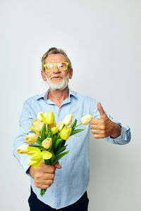 Cropped hands of woman holding flowers against white background