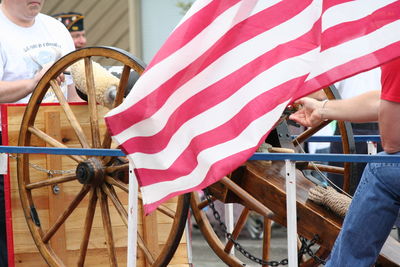 Men by cannon and american flag on street during fourth of july parade