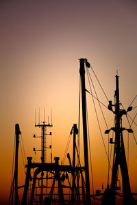 Silhouette cranes against clear sky during sunset