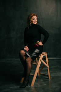 Portrait of woman sitting on chair against wall