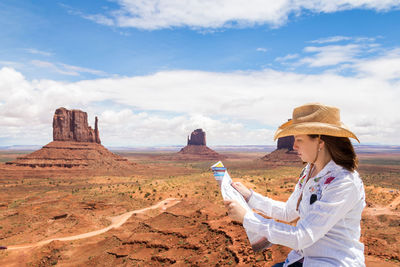 Woman standing on rock formations against sky