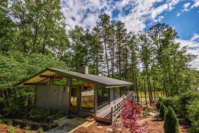 House amidst trees and plants in forest against sky