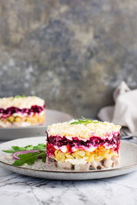 Herring under a fur coat traditional christmas salad on a plate on the table. vertical view