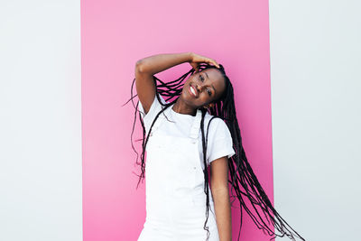 Portrait of smiling young woman standing against blue background