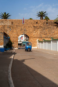 Tuk-tuk driving through a historical gate in the old medina of asilah